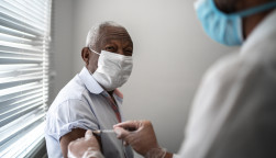 Nurse applying vaccine on patient's arm using face mask