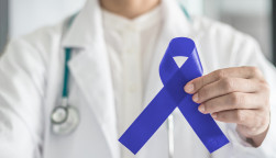 Dark blue ribbon for colon - colorectal cancer awareness on medical doctor's hand