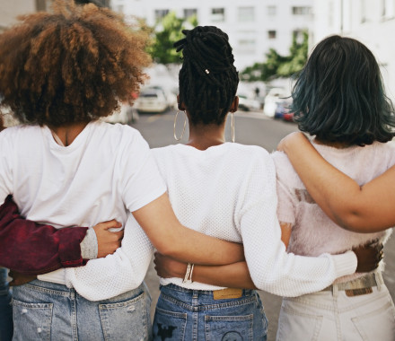 Rearview shot of a group of unrecognizable young friends walking with their arms around each other in the city