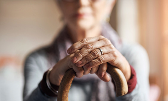 old woman, her hands resting on a cane